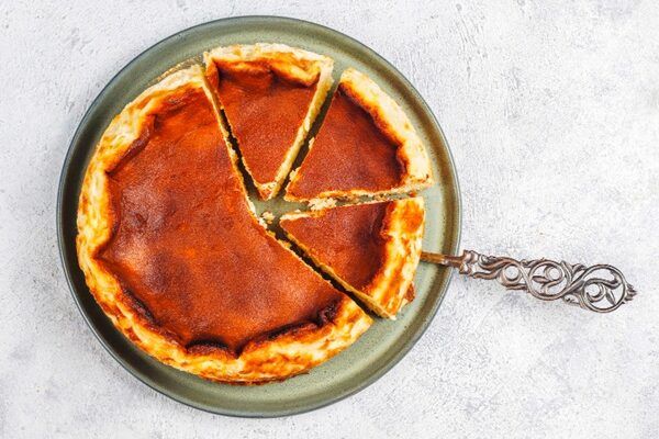 Tarta de queso de La Viña de San Sebastián presentada en plato junto a cuchara de servir