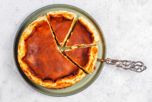 Tarta de queso de La Viña de San Sebastián presentada en plato junto a cuchara de servir