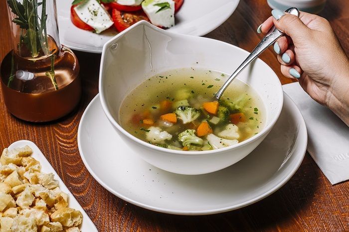 Sopa de verduras servida con hierbas