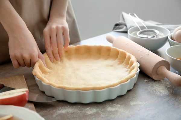 Mujer poniendo en molde la masa de la tarta de manzana