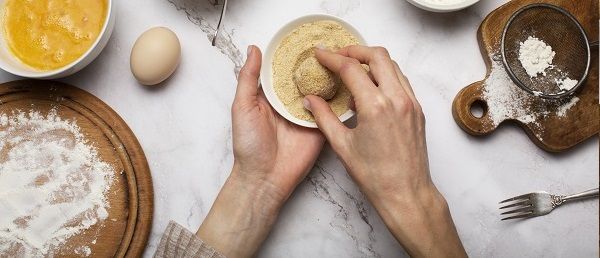 Chef pasando arancini por pan rallado