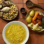 Cocido madrileño auténtico tradicional presentado en tres platos diferentes con los fideos, garbanzos, carnes y verduras