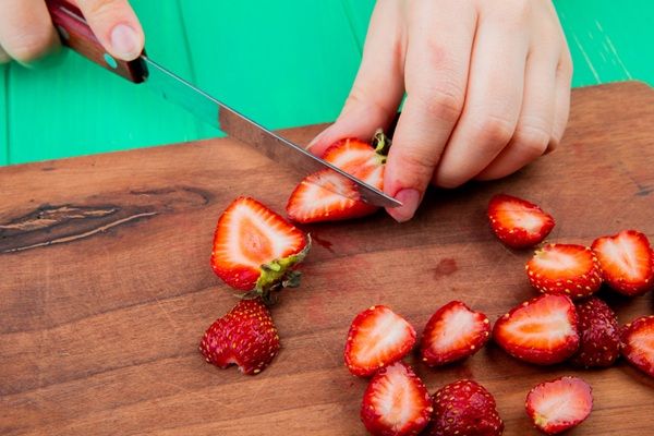 Chef cortando fresas encima de una madera