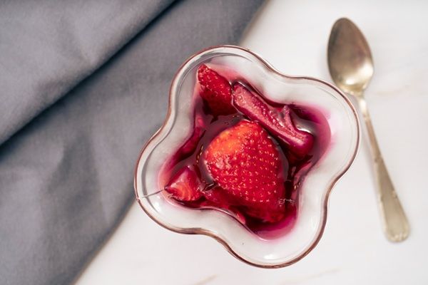Fresas en vinagre y azúcar presentadas en tarrito blanco con cuchara de metal