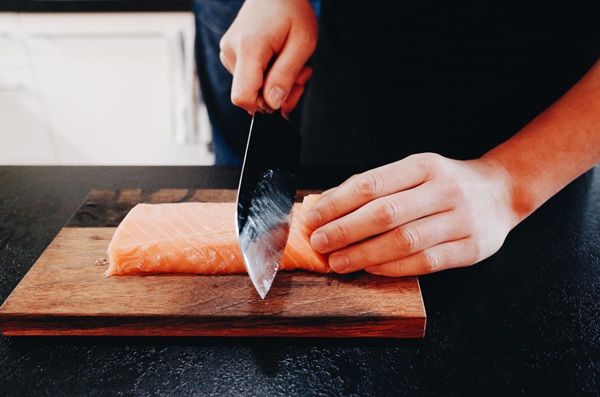 Chef cortando el salmón en tiras con un cuchillo