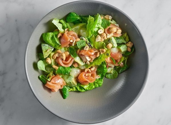 Ensalada fresca con salmón, queso suave, cacahuetes y menta vista desde arriba presentada en bol