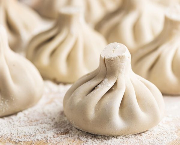 Khinkali formado encima de tabla de madera con harina