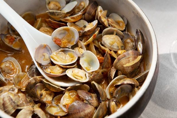 Almejas en salsa de tomate casera dentro de olla y una cuchara dentro lista para servir