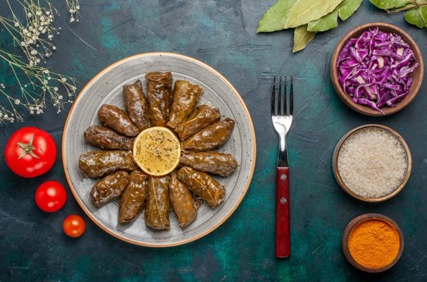 Dolmas presentados en plato blanco junto a ingredientes alrededor