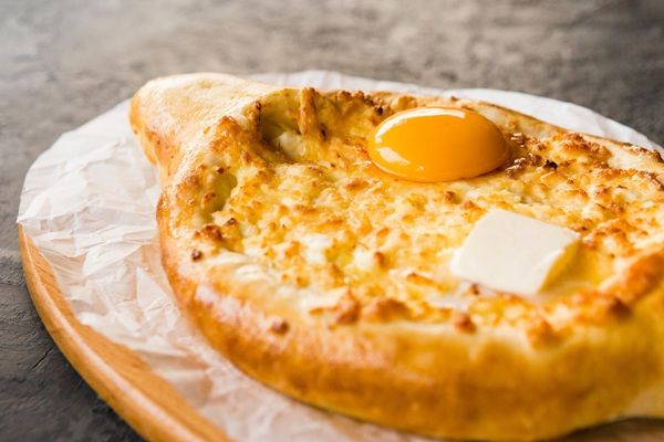 Khachapuri horneado con huevo encima y trozo de mantequilla