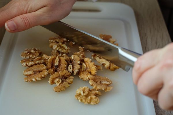 Chef picando nueces con cuchillo sobre tabla