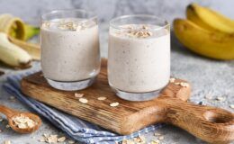 Batidos de plátano y avena sobre tabla de madera e ingredientes alrededor