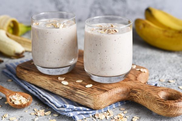 Batidos de plátano y avena sobre tabla de madera e ingredientes alrededor