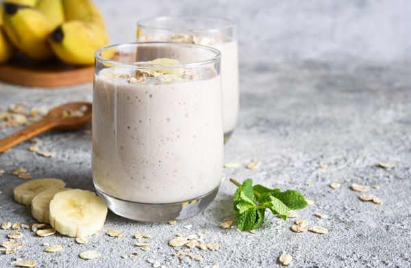 batidos-platanos-avena Batidos de plátano y avena con ingredientes alrededor y plátanos al fondo