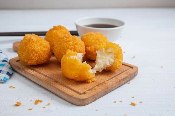 Bolitas de queso deliciosas sobre tabla de madera