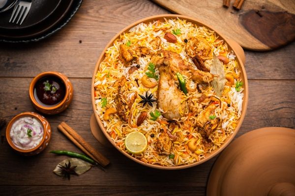 Imagen de biryani de pollo con salsas al lado