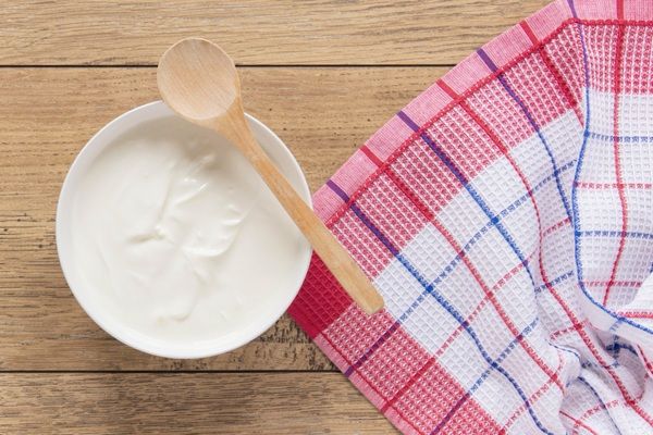 Imagen de yogur natural con cuchara de palo y paño al lado